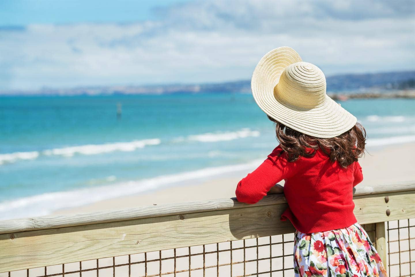 kvinde med solhat kigger ud af havet om sommeren