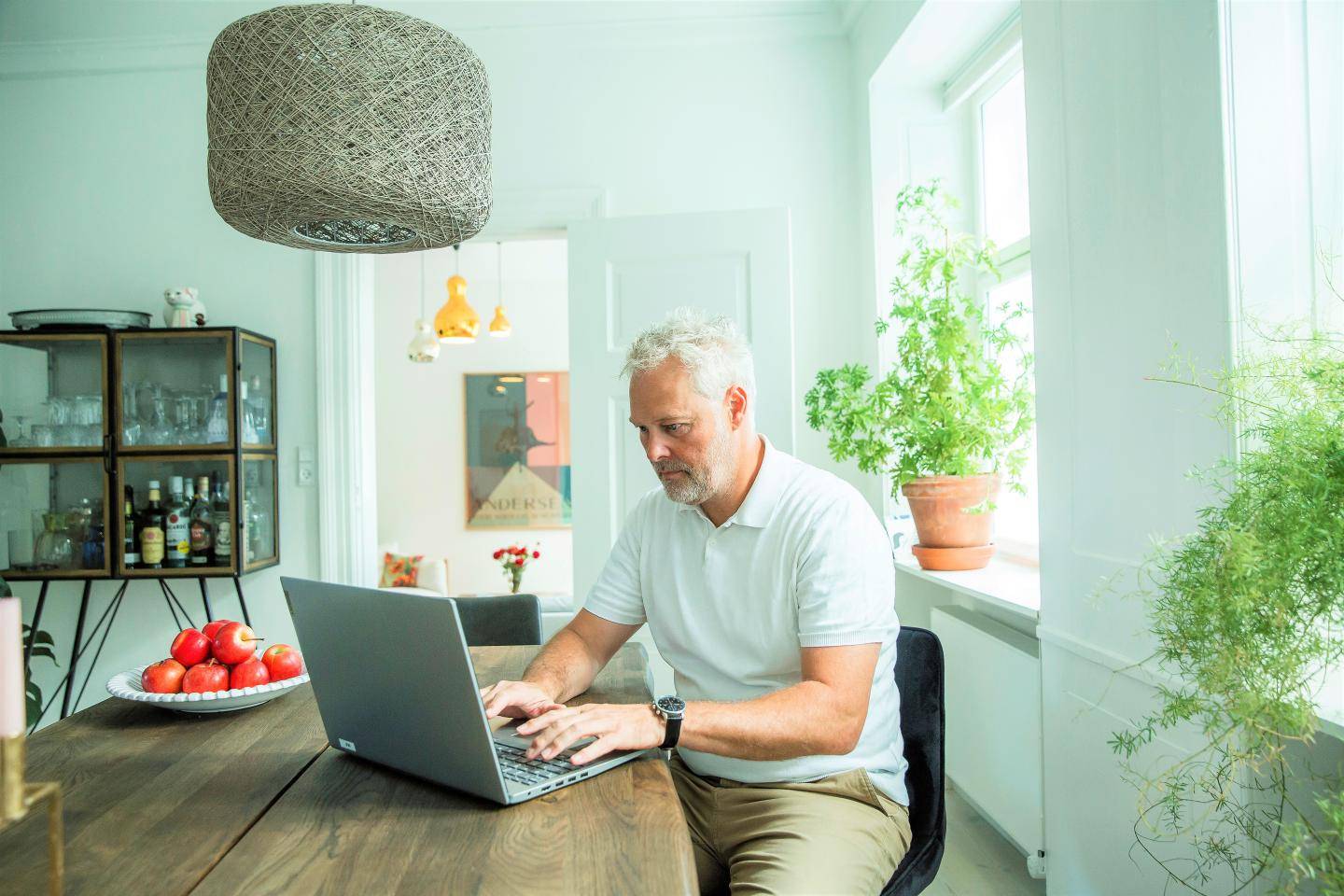 Mand, der sidder ved et spisebord med sin computer