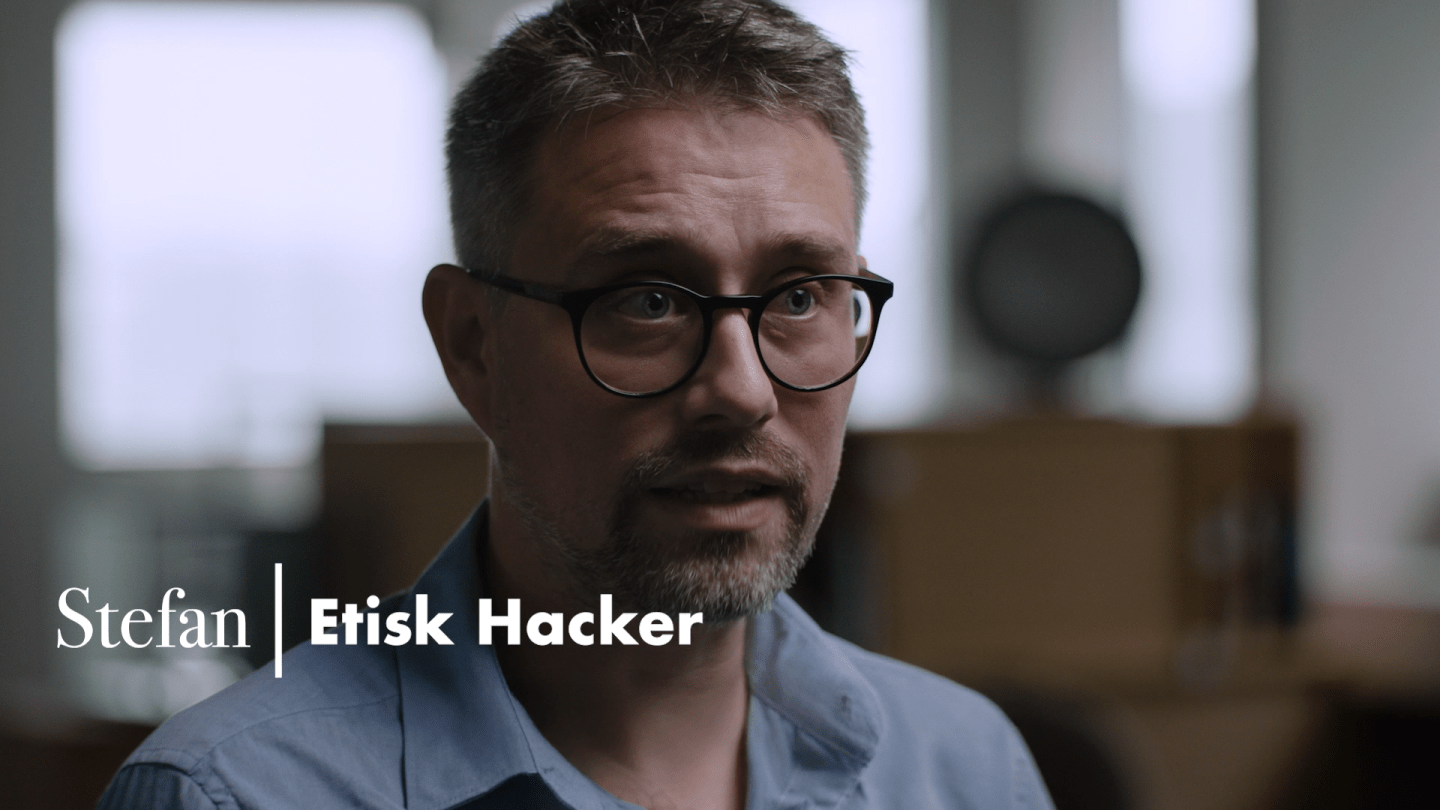 Mand med skjorte og briller ses i foregrunden. 