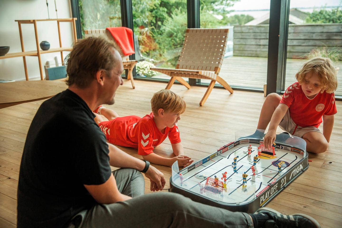 Børn og far sidder på gulvet og leger, fotografi