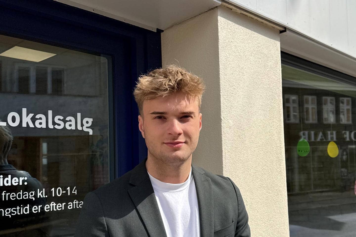 Mand står foran dør ved forretning, fotografi